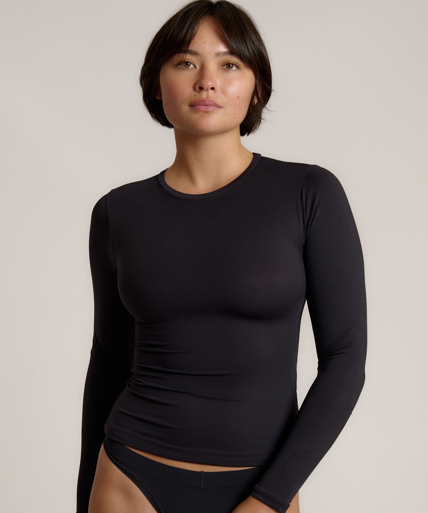 Person wearing a black long-sleeve against a plain background