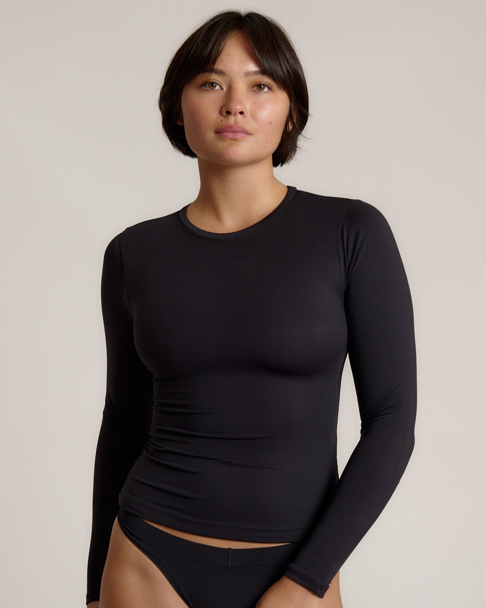 Person wearing a black long-sleeve against a plain background
