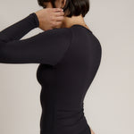 Person wearing a black long-sleeve against a plain background