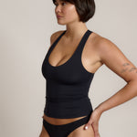 Woman wearing a black racerback against a plain background
