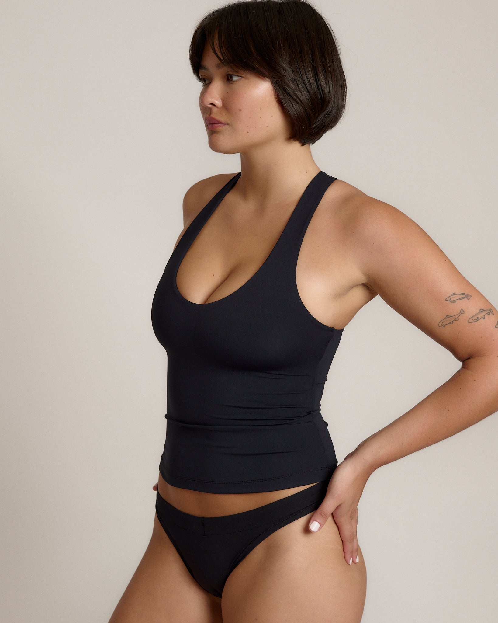 Woman wearing a black racerback against a plain background
