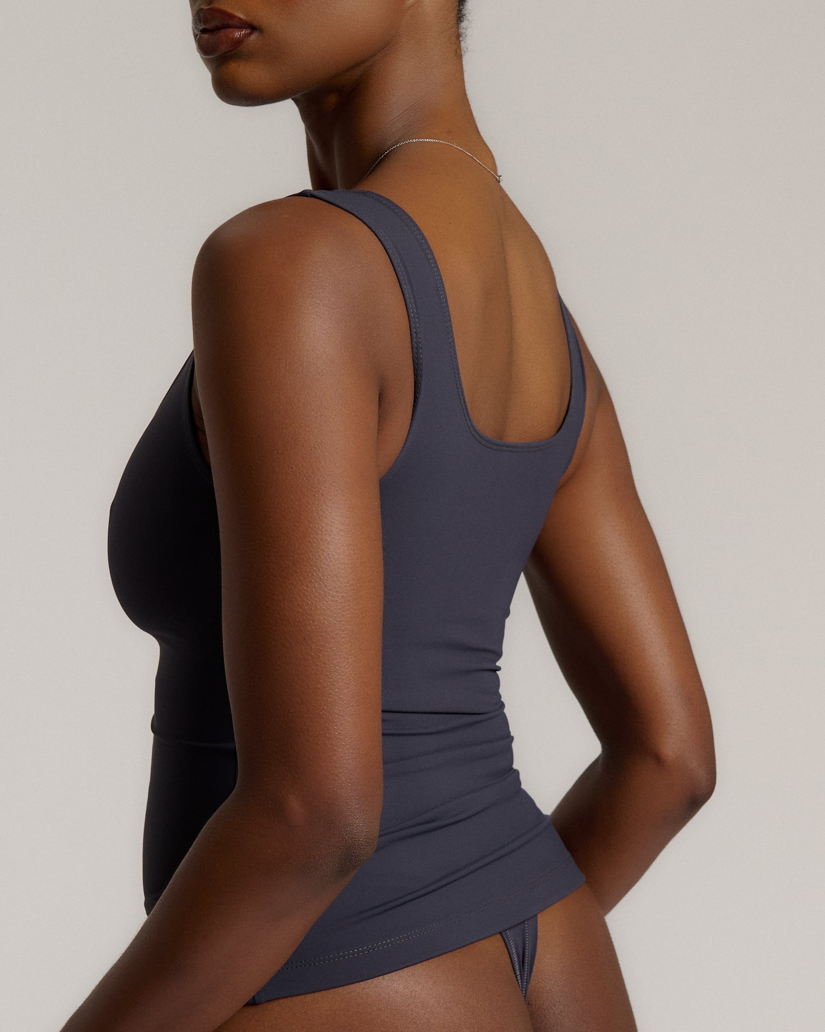 A woman modeling a myst scoop-neck tank top and a matching thong against a plain light gray studio background.