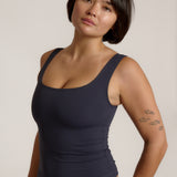 A woman modeling a myst scoop-neck tank top and a matching thong against a plain light gray studio background.