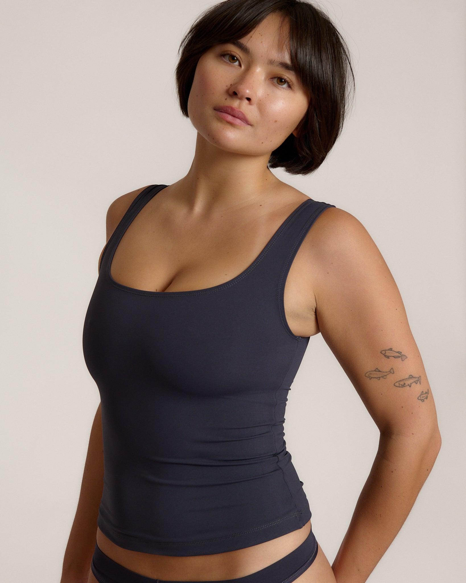 A woman modeling a myst scoop-neck tank top and a matching thong against a plain light gray studio background.