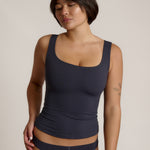 A woman modeling a myst scoop-neck tank top and a matching thong against a plain light gray studio background.
