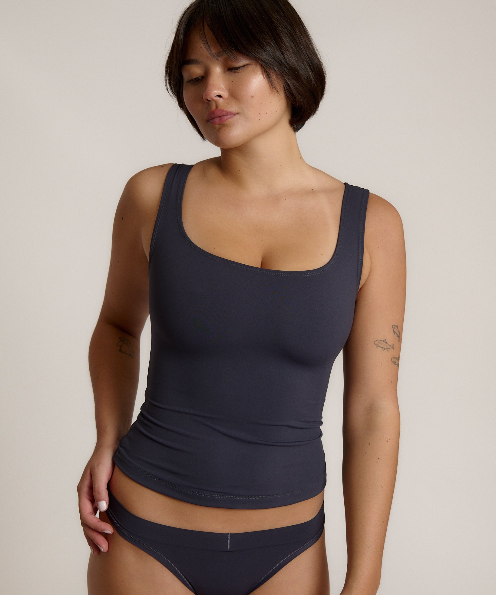 A woman modeling a myst scoop-neck tank top and a matching thong against a plain light gray studio background.