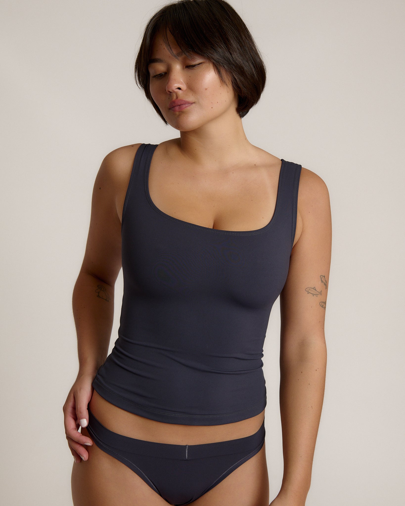 A woman modeling a myst scoop-neck tank top and a matching thong against a plain light gray studio background.