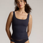 A woman modeling a myst scoop-neck tank top and a matching thong against a plain light gray studio background.