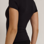 Woman wearing a black t-shirt against a plain background