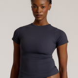 A woman modeling a myst tee and a matching thong against a plain light gray studio background.