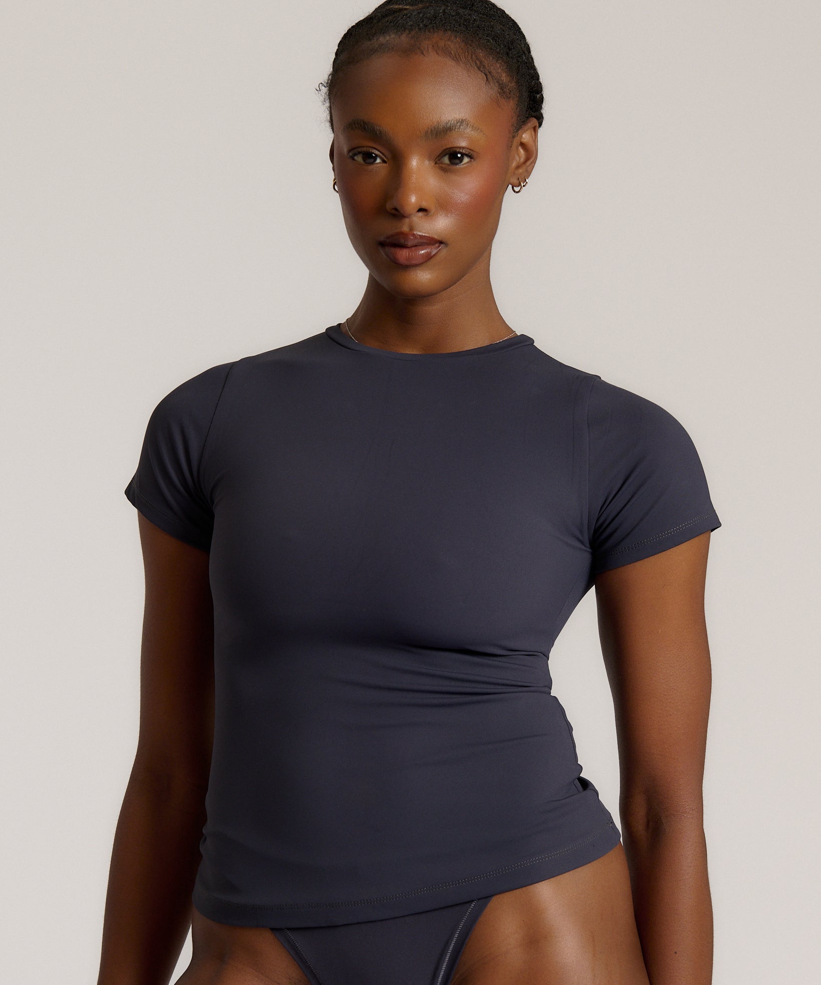 A woman modeling a myst tee and a matching thong against a plain light gray studio background.