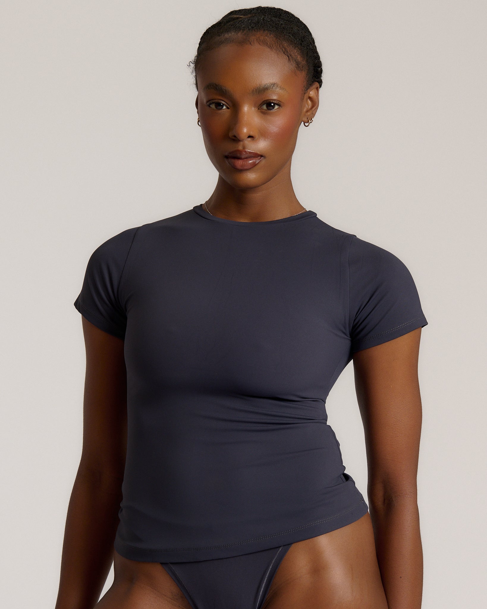 A woman modeling a myst tee and a matching thong against a plain light gray studio background.
