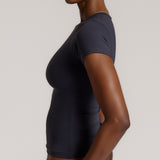 A woman modeling a myst tee and a matching thong against a plain light gray studio background.
