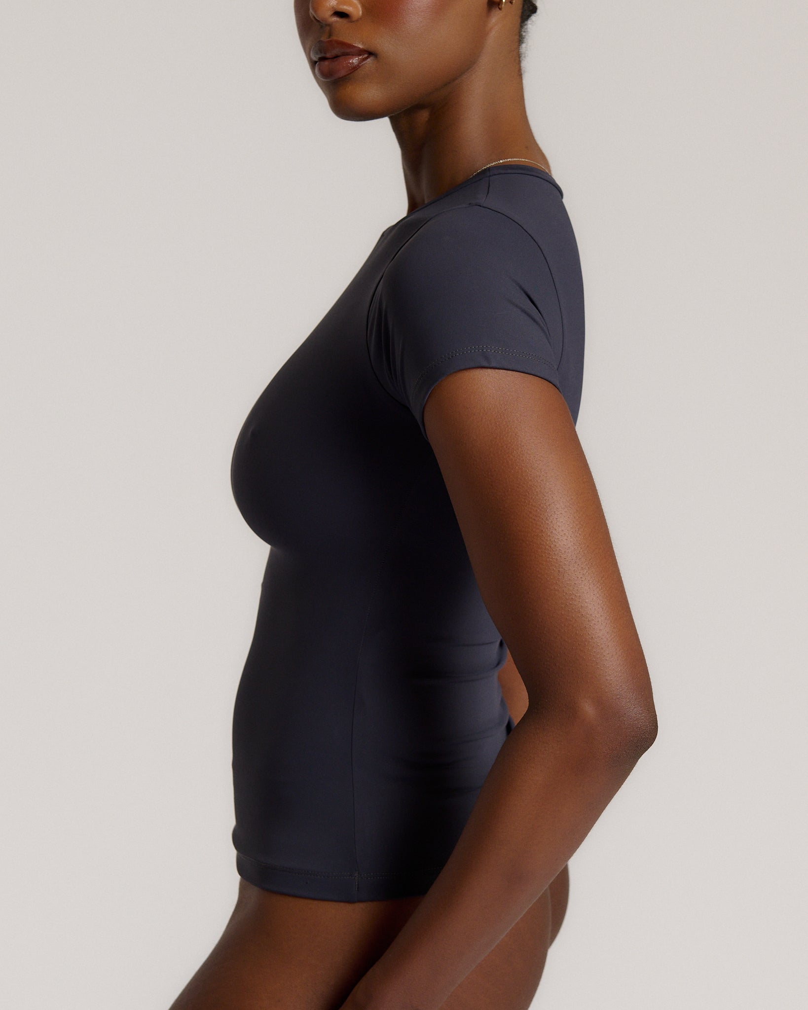 A woman modeling a myst tee and a matching thong against a plain light gray studio background.