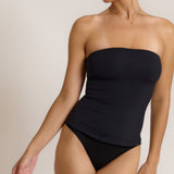 Woman wearing a black strapless top against a gray background