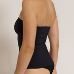 Woman wearing a black strapless top against a gray background