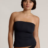 Woman wearing a black strapless top against a gray background