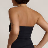 Woman wearing a black strapless top against a gray background