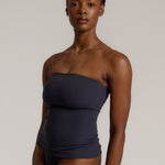 A woman modeling a myst tube top and a matching thong against a plain light gray studio background.
