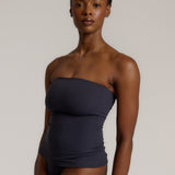 A woman modeling a myst tube top and a matching thong against a plain light gray studio background.