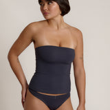 A woman modeling a myst tube top and a matching thong against a plain light gray studio background.