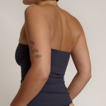 A woman modeling a myst tube top and a matching thong against a plain light gray studio background.