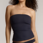 A woman modeling a myst tube top and a matching thong against a plain light gray studio background.