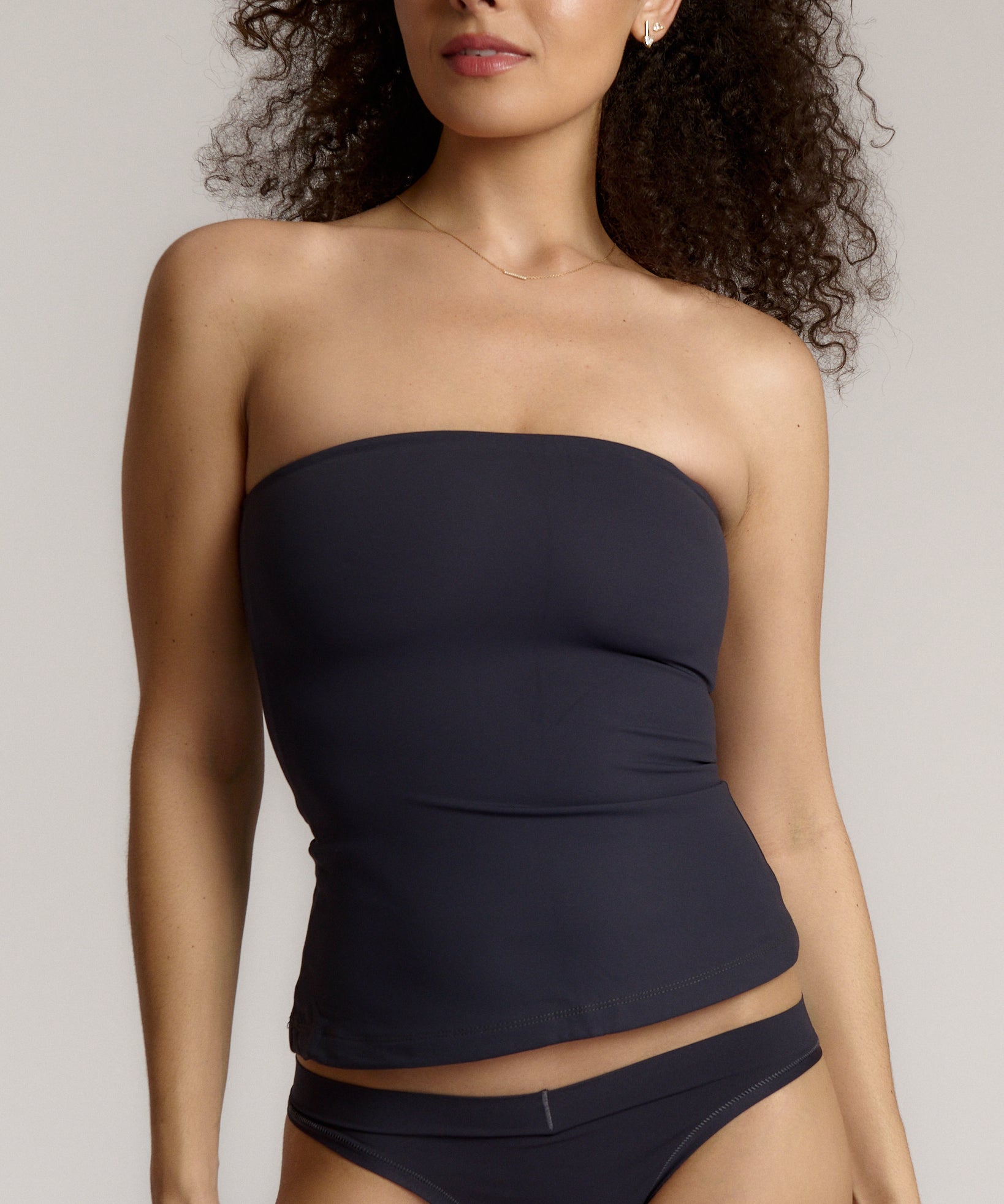 A woman modeling a myst tube top and a matching thong against a plain light gray studio background.