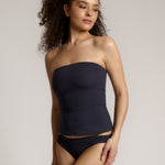 A woman modeling a myst tube top and a matching thong against a plain light gray studio background.