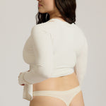 Woman wearing a white wrap top against a plain background