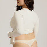 Woman wearing a white wrap top against a plain background