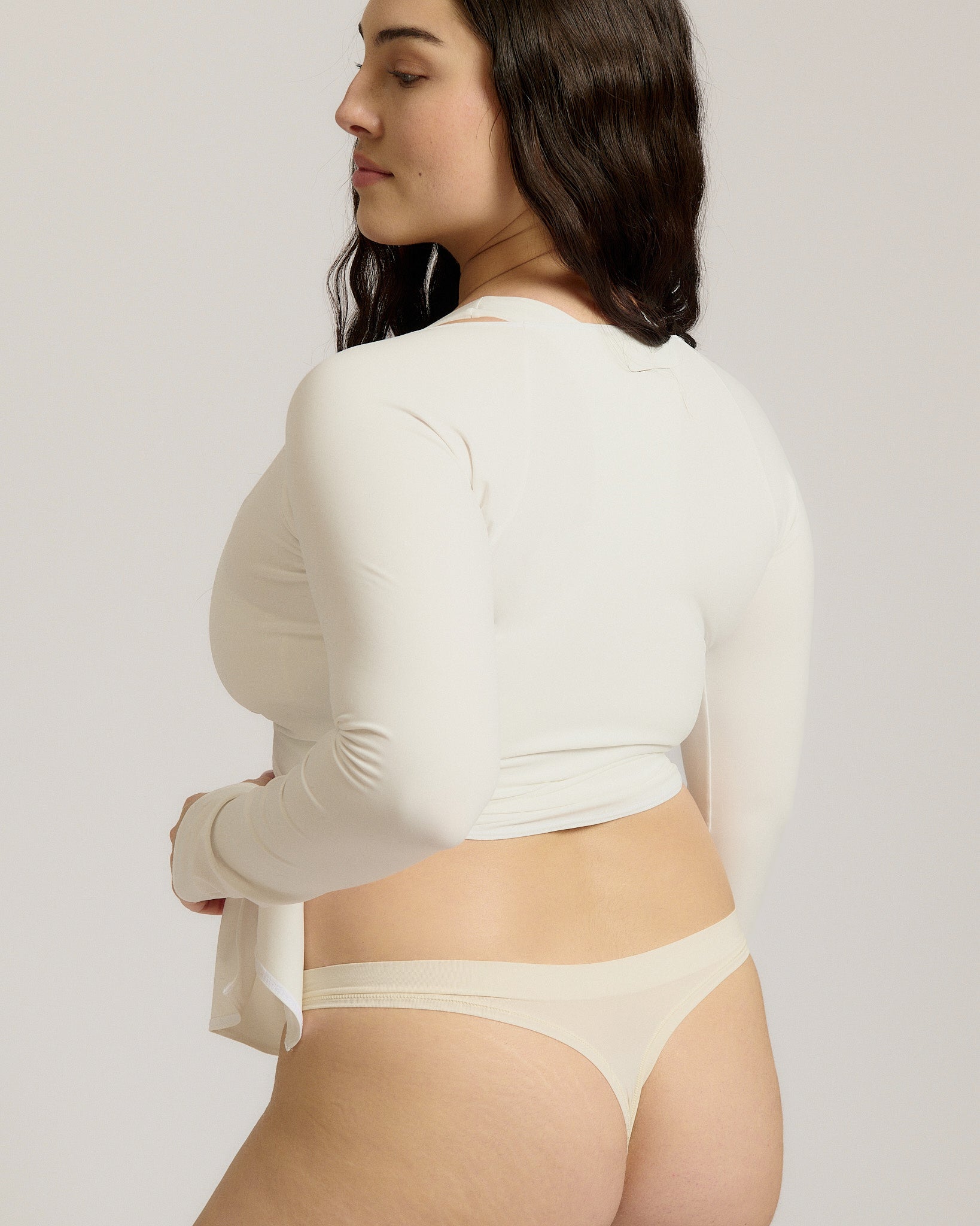 Woman wearing a white wrap top against a plain background