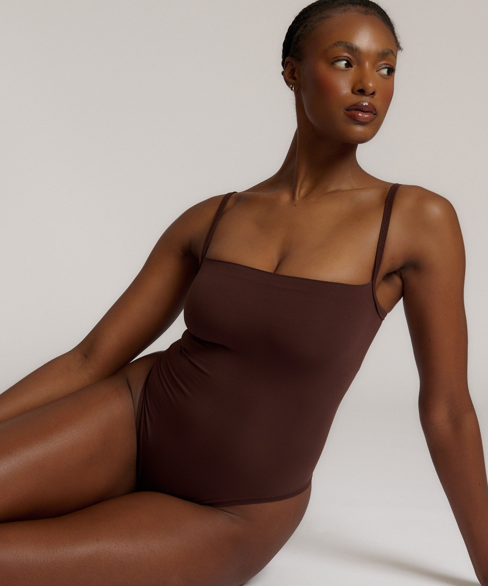 A woman wearing a brown square neck bodysuit with thin straps.