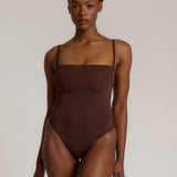 A woman wearing a brown square neck bodysuit with thin straps.