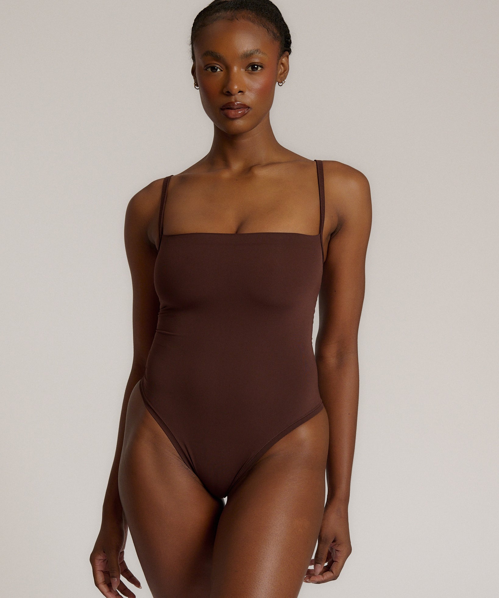 A woman wearing a brown square neck bodysuit with thin straps.