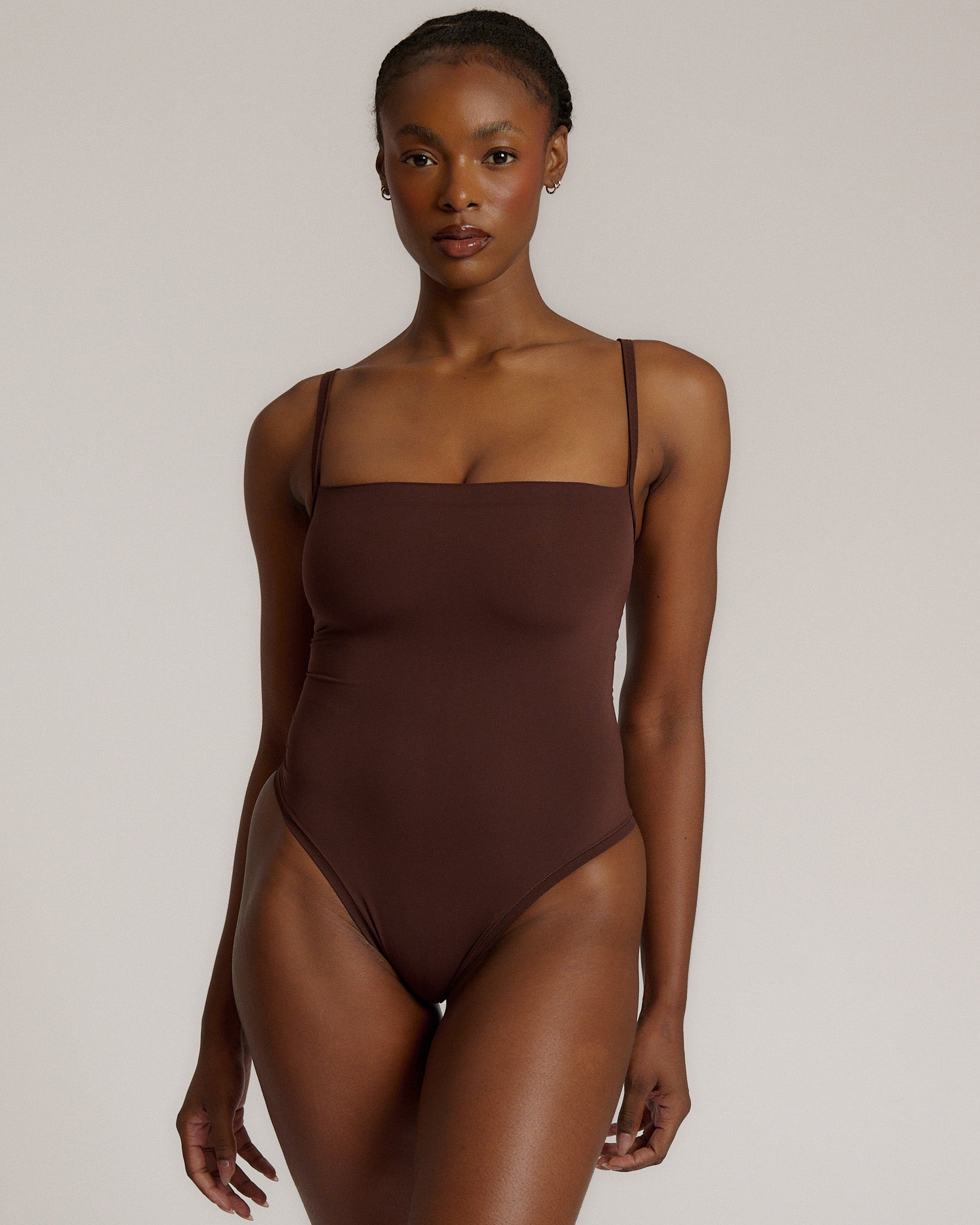A woman wearing a brown square neck bodysuit with thin straps.