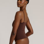 A woman wearing a brown square neck bodysuit with thin straps.