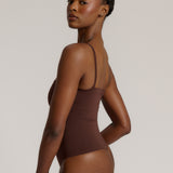 A woman wearing a brown square neck bodysuit with thin straps.