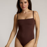 A woman wearing a brown square neck bodysuit with thin straps.