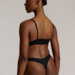Person wearing a black cami system against a plain background