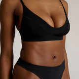 Person wearing a black cami system against a plain background