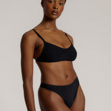 Woman wearing black scoop system against a neutral background