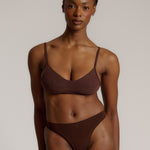A person wearing a mocha thong and scoop system on a plain background.