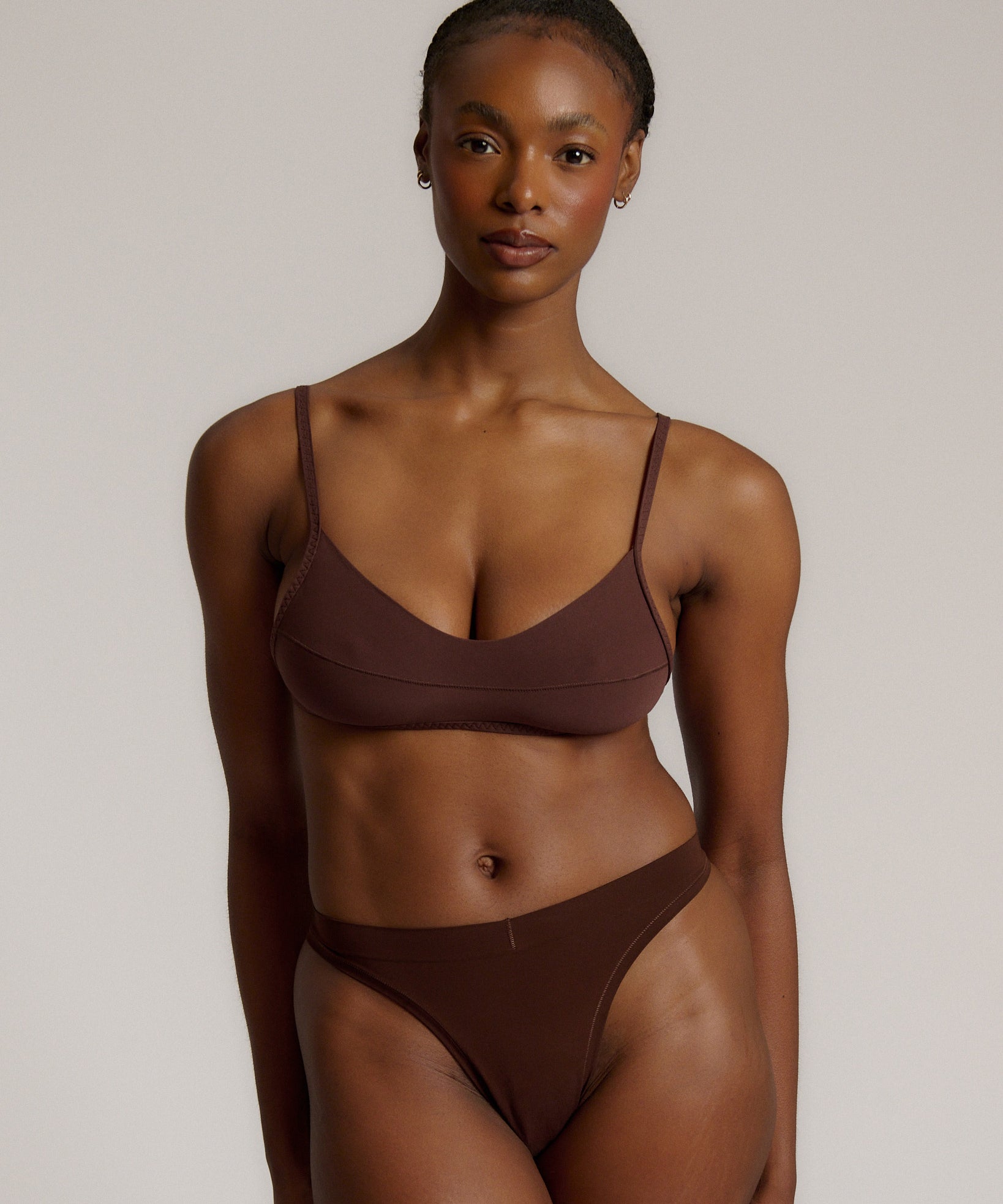 A person wearing a mocha thong and scoop system on a plain background.
