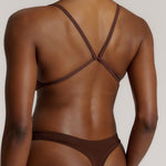 A person wearing a mocha thong and scoop system on a plain background.