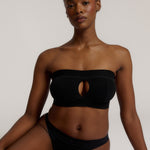 Woman wearing black strapless system against a neutral background