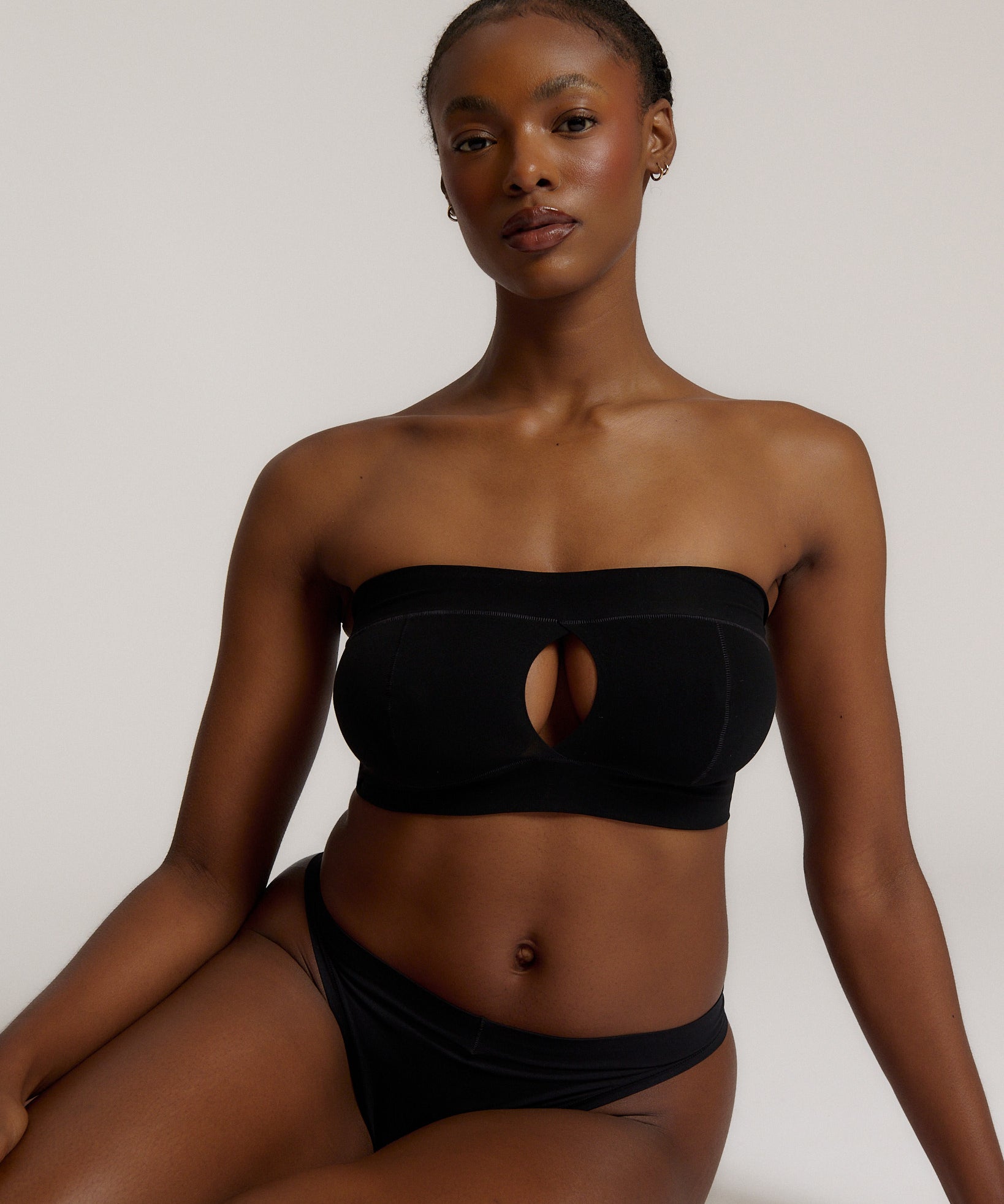 Woman wearing black strapless system against a neutral background