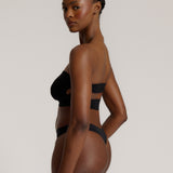 Woman wearing black strapless system against a neutral background