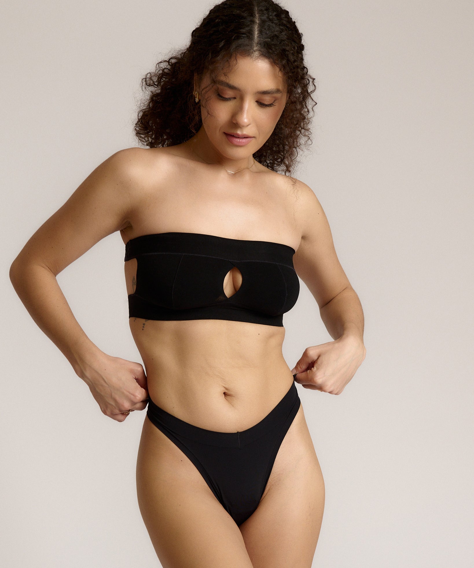 Woman wearing black strapless system against a neutral background