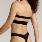 Woman wearing black strapless system against a neutral background